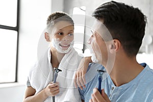 Happy father and son with shaving foam on their faces