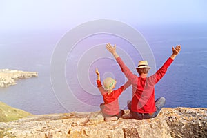 Happy father and son sitting on top of a mountain