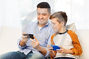 Happy father and son with smartphones at home