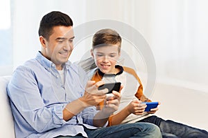 Happy father and son with smartphones at home