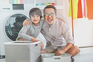 Happy Father and son is smiling and laughing while doing laundry together at home for Family togetherness concept