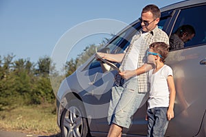 Happy father and son standing near the car at the day time