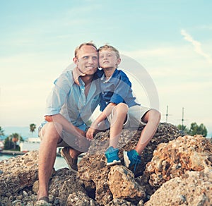 Happy father and son in sunset sea harbor