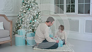 Happy father and son unwrapping a present sitting on the floor