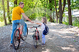 Happy father teaches his daughter to ride a bike. Family spending time together