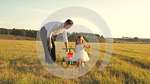 Happy father teaches little daughter to ride a bike. Dad plays with small child on lawn. kid learns to ride bicycle