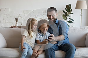 Happy father teaching daughter and son kids to use app