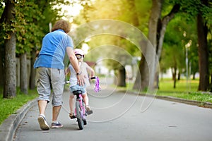 Happy father teaching his little daughter to ride a bicycle. Child learning to ride a bike.