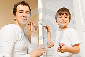 Happy father teaching his son to fix door-handle