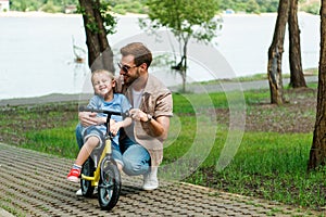 happy father teaching son riding bike