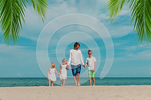 happy father and three kids walking on beach