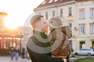 A happy father and three year old son hug in a city street. Warm relationships between parents and children.