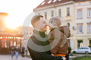 A happy father and three year old son hug in a city street. Warm relationships between parents and children. Spending time