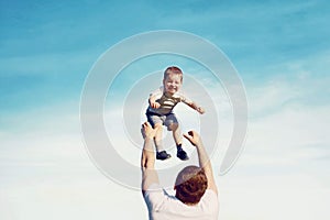 Happy father throwing his son child into the air, carefree having fun outdoors