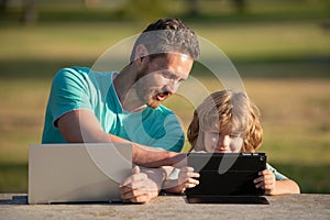 Happy father using laptop relax with schooler son holding laptop have fun together, smiling dad and little boy child