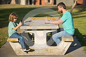 Happy father using laptop relax with schooler son holding laptop have fun together, smiling dad and little boy child