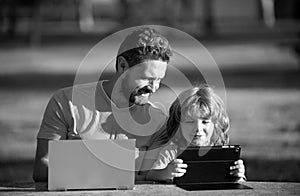 Happy father using laptop relax with schooler son holding laptop have fun together, smiling dad and little boy child