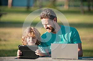 Happy father using laptop relax with schooler son holding laptop have fun together, smiling dad and little boy child