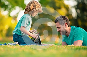 Happy father using laptop relax with schooler son holding laptop have fun together, smiling dad and little boy child