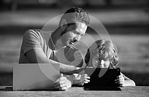 Happy father using laptop relax with schooler son holding laptop have fun together, smiling dad and little boy child