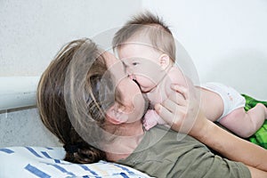 Happy father and wrinkling baby girl portrait lying on bed together