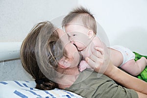 Happy father and wrinkling baby girl portrait lying on bed together photo