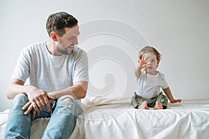 Happy father young man and baby girl little daughter having fun on bed in children room at home