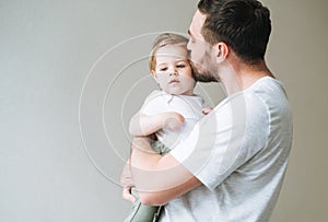 Happy father young man kissing baby girl little daughter at home