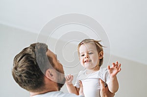 Happy father young man and baby girl little daughter having fun in children room at home