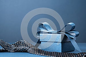 Happy Fathers Day background. gift box and necktie on blue table.