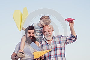 Happy fathers day. Childhood concept. Happy grandfather father and grandson with toy paper airplane over blue sky and