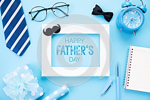 Happy fathers day concept. Top view of blue tie, beautiful gift box, alarm clock, white picture frame with Happy father`s day tex