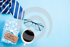 Happy fathers day concept. Top view of blue tie, beautiful gift box, coffee mug, glasses with LOVE DAD text on bright blue pastel