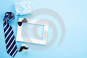 Happy fathers day concept. Top view of blue tie, beautiful gift box, coffee mug, white picture frame with happy father`s day text