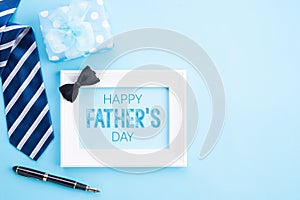 Happy fathers day concept. Top view of blue tie, beautiful gift box, coffee mug, white picture frame with happy father`s day text