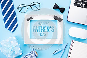 Happy fathers day concept. Top view of blue tie, beautiful gift box, laptop computer, white picture frame with Happy father`s day