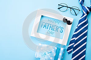 Happy fathers day concept. Top view of blue tie, beautiful gift box, white picture frame with Happy father`s day text on bright