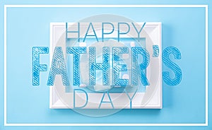 Happy fathers day concept. Top view of picture frame and gift box with happy father`s day text on blue pastel background. Flat la