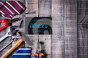 Happy fathers day concept. Top view of white picture frame with border of tools and ties, retro film camera on dark wooden table