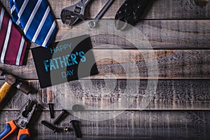 Happy fathers day concept. Top view of white picture frame with border of tools and ties, retro film camera on dark wooden table