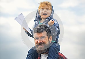 Happy fathers day. Dad and son are playing on sky background. Child sits on the shoulders of his father. Freedom to