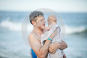 Happy Fathers day. Father and baby play on the beach. Dad and him Child together enjoying sunset. Loving single father hugs cute