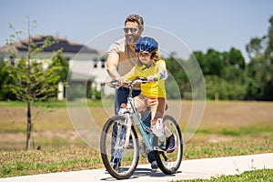 Happy Fathers day. Father and son on the bicycle. Father and son riding a bike in summer park. Kid learning to riding