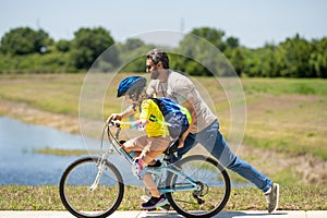 Happy Fathers day. Father and son in bike helmet for learning to ride bicycle at park. Father helping son cycling