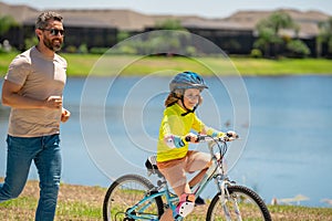 Happy Fathers day. Father and son in bike helmet for learning to ride bicycle at park. Father helping son cycling