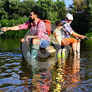 Happy fathers day. Father teaching son how to fly-fish in river. Grandpa and grandson are fly fishing on river. Men