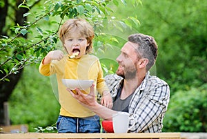 Happy fathers day. Little boy with dad eat cereal. father and son eating outdoor. Morning breakfast. Vegetarian diet