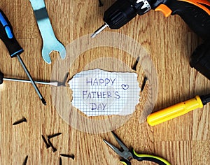 Happy Fathers Day with tools on a rustic wood background.