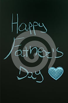 Happy fatherâ€™s day greetings handwritten on blackboard decorated with blue heart