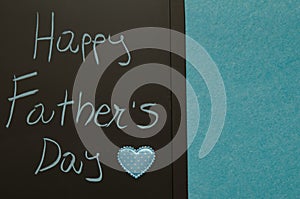 Happy fatherâ€™s day greetings handwritten on blackboard decorated with blue heart